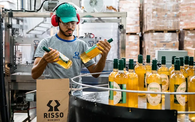 Colaborador da Risso conferindo garrafas na linha de produção